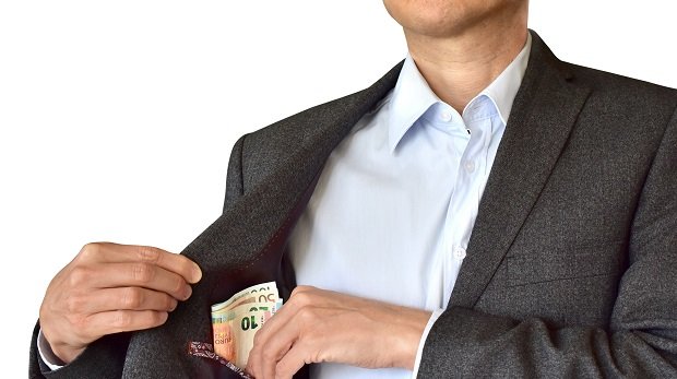Symbolbild für einen Mann, der sich Geld in die Tasche steckt.