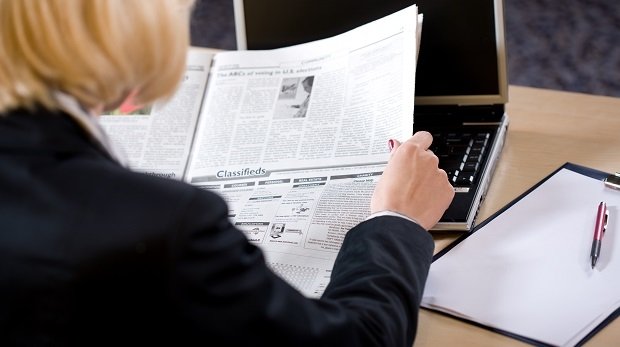 Eine Entscheiderin liest Zeitung am Schreibtisch (Symbolbild)