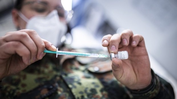 Soldatin zieht eine Spritze mit einer Corona-Impfung auf