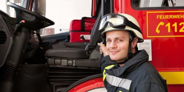 Feuerwehrmann vor seinem Dienstfahrzeug