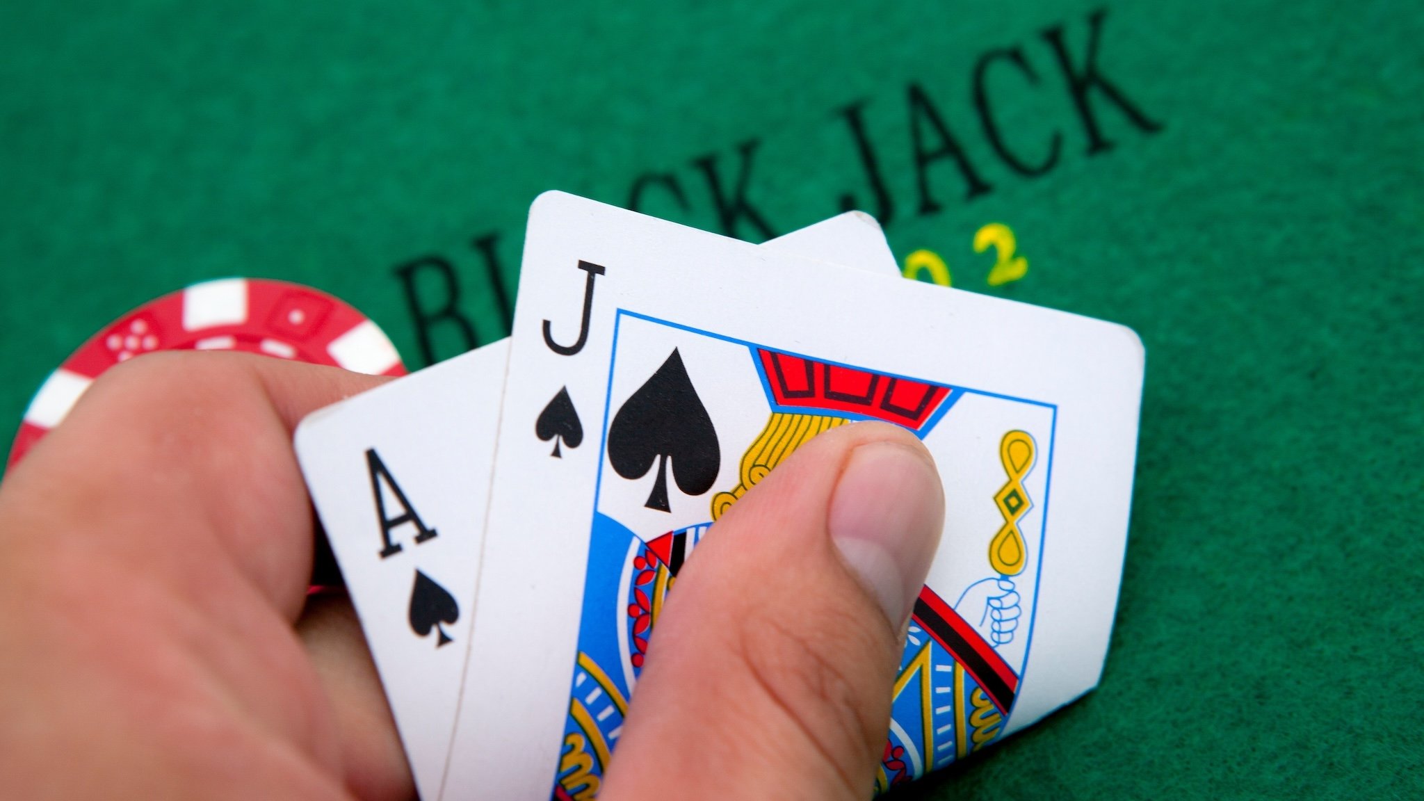 Black-Jack-Tisch, Hand hält zwei Spielkarten (Pik Ass und Pik Bube)