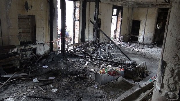 Ein im Rahmen der Ausschreitungen abgebranntes Gebäude, in dessen Inneren Trauernde Blumen abgelegt haben