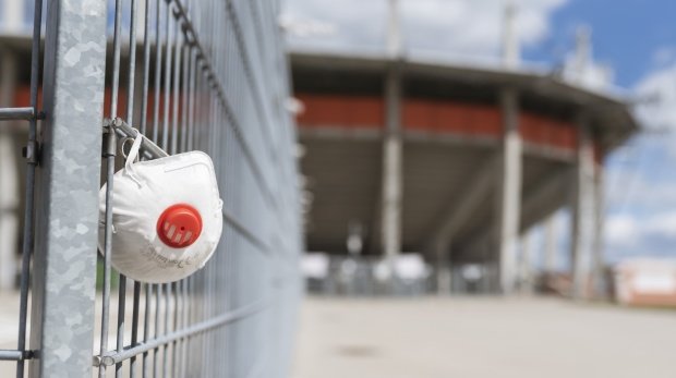 Atemschutzmaske vor einem Stadion
