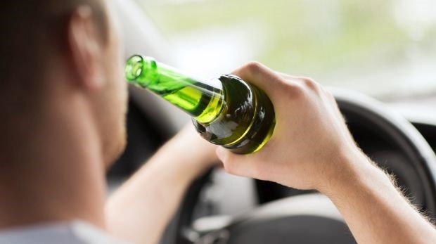 Mann trinkt Bier während der Autofahrt