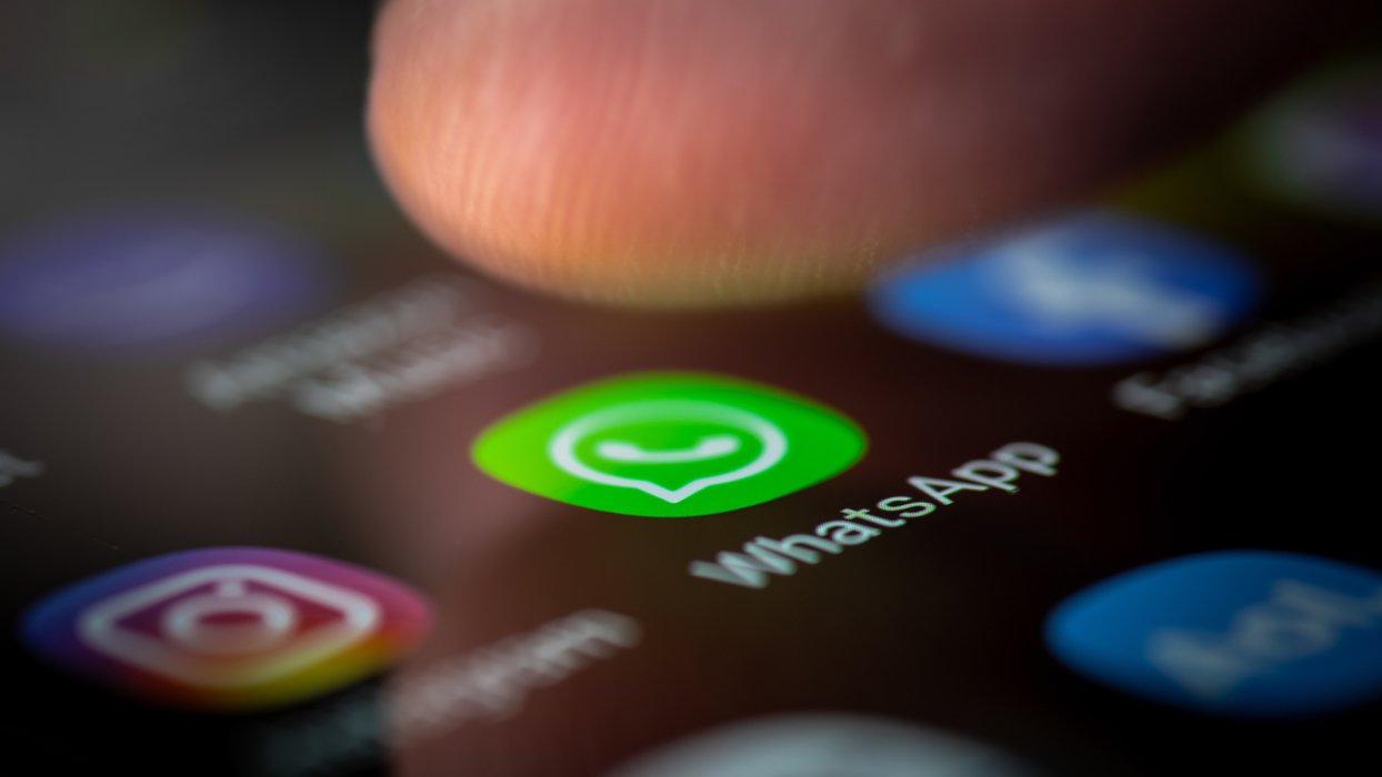 Eine Person tippt mit dem Finger auf das Appsymbol von WhatsApp auf dem Smartphone