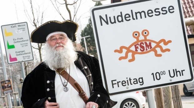 Rüdiger Weida von der "Kirche der fliegenden Spaghettimonster" neben seinem Schild "Nudelmesse" in Templin (Brandenburg)