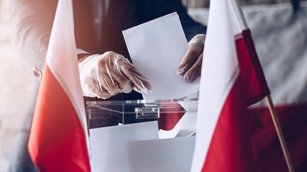 Mann mit Handschuhen, Wahlurnen, polnische Flaggen