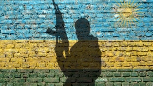 Schatten eines Soldaten auf einer Mauer mit der Ruandischen Flagge