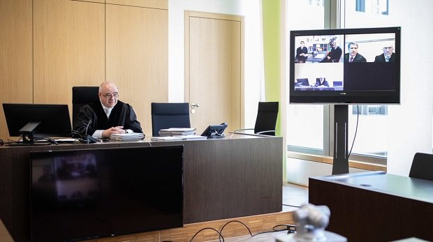 Hartwig Ollerdißen, Vorsitzender Richter am Landgericht, sitzt im Gerichtssaal vor einer Kamera und Bildschirmen.