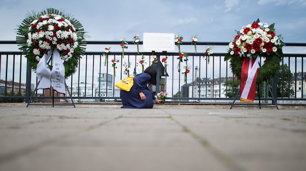 Eine Frau legt einen Strauß Blumen am Gedenkort für den Wehrhahn-Anschlag am Bahnhof Wehrhahn nieder.