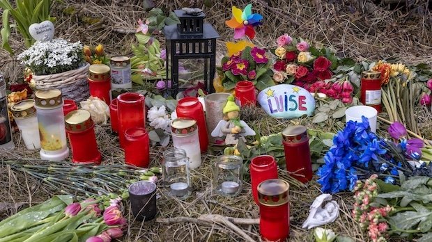 Kerzen, Blumen, Kuscheltiere und ein bunt bemalter Stein mit dem Namen Luise an der Stelle im Wald, an der die Menschen in Freudenberg Abschied von Luise nehmen.