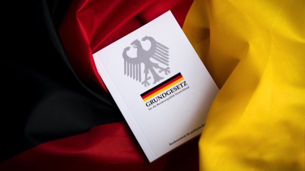 Eine Ausgabe des Grundgesetzes auf der deutschen Nationalflagge.
